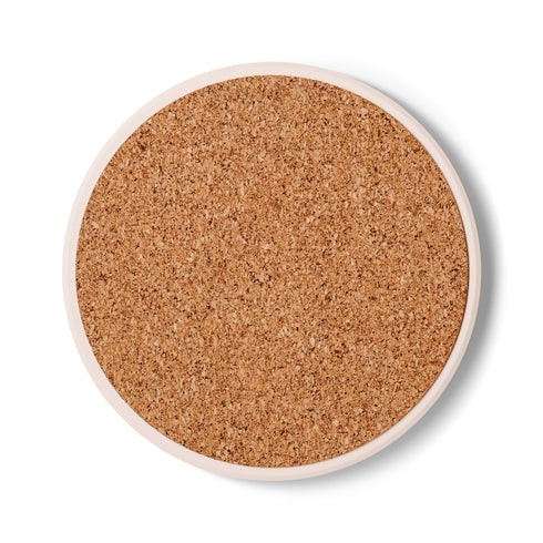 A round ceramic coaster with a smooth, matte, dark slate-blue surface and a natural, textured cork backing. The top of the coaster features an intricate, metallic gold line-art design of the All-Seeing Eye, also known as the Eye of Providence. A central eye with a defined iris and pupil is enclosed within a circular emblem, from which fine golden lines radiate outwards like beams of light. Below the eye, two stylized laurel branches curve upwards, cradling a small, four-pointed star.