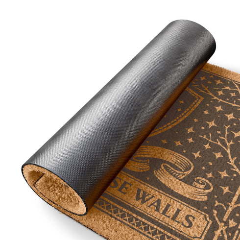 A rectangular eco-friendly coir doormat measuring 24 by 16 inches displayed on a stone porch. The natural golden-brown coconut fiber mat features a bold black graphic design of a heraldic bear head centered on a medieval knight's shield. Above and below the shield, Gothic-style typography reads BLESSED WITHIN THESE WALLS. The mat has a durable black vinyl non-slip backing. Ideal for Castlecore, Dark Academia, and Grimoire and Goblet style gothic home decor themes.