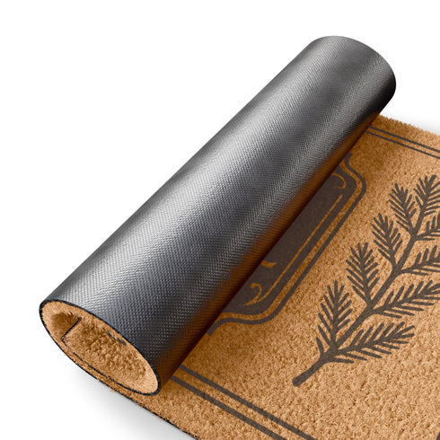 A rectangular tufted coir doormat from Grimoire and Goblet. The mat is a natural, textured brown, providing a high-contrast background for the black, gothic-style design. In the center, a decorative plaque, reminiscent of a vintage grimoire page, features the words "ENTER WITH PEACEFUL INTENT" in a serif font. Above the text is a small celestial crescent moon and star. Flanking the central plaque are two large, symmetrical botanical laurels or fern branches.
