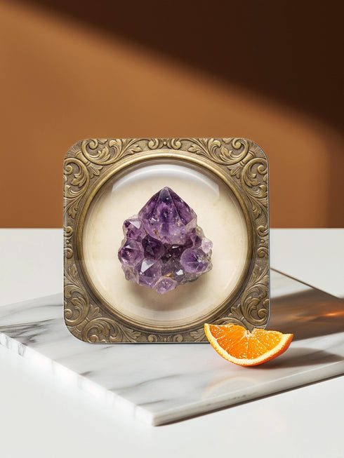 Grimoire and Goblet set of four square glossy coasters featuring high-resolution printed illustrations of raw crystals: purple amethyst, pink rose quartz, iridescent labradorite, and banded agate. Each gemstone is depicted inside a printed faux antique brass baroque frame with intricate scrollwork, set against a cream parchment background. The design is a flat 2D trompe l'œil print on hardboard, creating a realistic 3D specimen box illusion.
