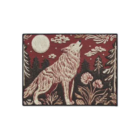 A rectangular Grimoire and Goblet doormat featuring a howling wolf standing in a dark forest under a full cream moon. The design utilizes a rust red and deep brown color palette with a high-fidelity 2D print technique that mimics the texture of vintage tapestry needlepoint. Stylized pine trees and forest flora surround the wolf. The mat has black trim and is made of smooth polyester, creating a rustic cottagecore aesthetic without actual raised threads or embroidery.