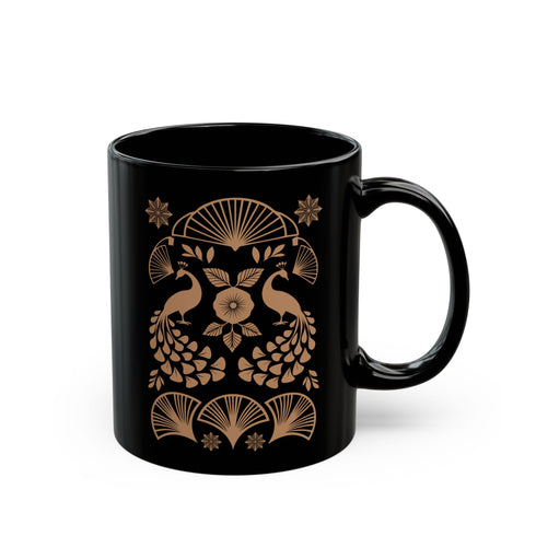 A black ceramic mug featuring an Art Deco-inspired design in rose gold. The symmetrical pattern shows two peacocks with fan-shaped tails, surrounded by ginkgo fan motifs and floral elements. The central design includes a stylized flower with leaves, and decorative stars accent the composition. The mug has a classic C-shaped handle.