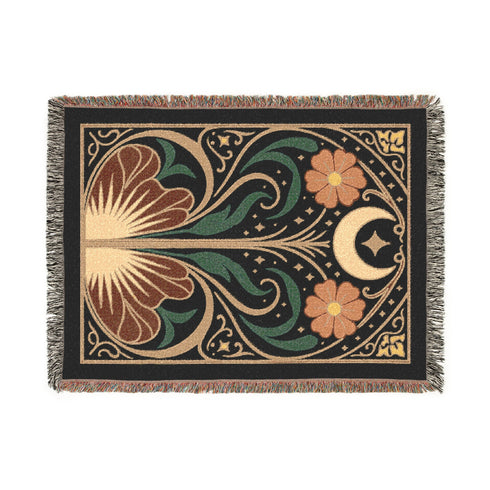A luxurious, intricately woven jacquard blanket from Grimoire and Goblet. The design is a symmetrical Art Nouveau botanical pattern on a dark teal background. A central stem with green leaves swirls upwards, flanked by two large, rust-orange flowers. At the top, a golden crescent moon and star sparkle. A fan-like, sun-inspired motif rests at the base. The entire piece, crafted from 100% cotton, is framed by a decorative gold border and a multi-colored fringe.