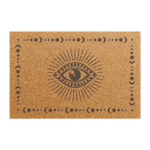 Rectangular coir doormat with central evil eye symbol surrounded by lunar phases, in natural tan with black designs.
