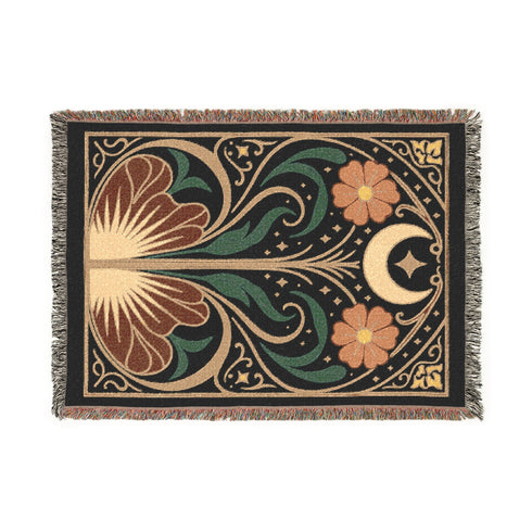 A luxurious, intricately woven jacquard blanket from Grimoire and Goblet. The design is a symmetrical Art Nouveau botanical pattern on a dark teal background. A central stem with green leaves swirls upwards, flanked by two large, rust-orange flowers. At the top, a golden crescent moon and star sparkle. A fan-like, sun-inspired motif rests at the base. The entire piece, crafted from 100% cotton, is framed by a decorative gold border and a multi-colored fringe.