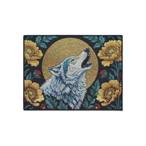 Grimoire and Goblet rectangular doormat featuring a faux embroidery style printed design of a howling wolf with blue and ivory fur, centered in front of a textured antique gold circular moon disc, surrounded by large golden yellow flowers, teal leaves, and small red berry accents on a dark charcoal background. Entryway rug with black trim, non slip backing, and botanical nature inspired mystical design.