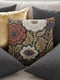 A square woven throw pillow featuring a surreal botanical design on a solid black background. The tapestry-style fabric showcases large, detailed flowers in shades of rust red, cream, and olive green. Nestled within the center of each prominent blossom is a detailed, human-like eye with a dark plum iris, creating a striking evil eye motif. The interwoven threads give the pillow a rich, textured appearance. The pillow is fully stuffed and sewn closed, presenting a smooth, seamless edge.