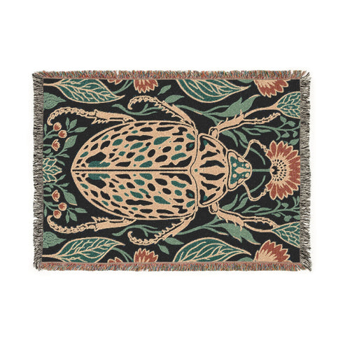 Jacquard woven 100% cotton blanket from Grimoire and Goblet featuring a detailed central beetle entomology motif and vintage botanical floral accents. The textile displays a rich woven texture with a fringe border in a dark academia palette of charcoal black, ochre, and rust. This heirloom-quality gothic tapestry functions as a decorative wall hanging or luxury throw for moody library and study interiors, showcasing high-fidelity thread-work and the brand's sorcerous aesthetic.