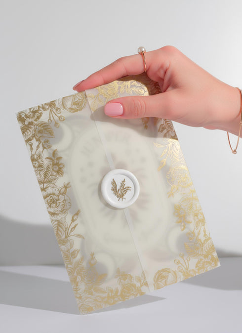 a luxury Grimoire and Goblet ritual card set. A 5x7 cream-colored folded card features an intricate, art-nouveau-style gold foil illustration of a Juniper plant, with the words "Juniper: Cleansing & Fortune." The card is presented with a translucent vellum envelope, which has a gold floral border and a white adhesive wax seal. Inside, the card reveals a vellum-wrapped keepsake, which unfurls to a 4x6 ritual card printed on thick, 160 GSM handmade cotton paper with a rough, deckled edge.