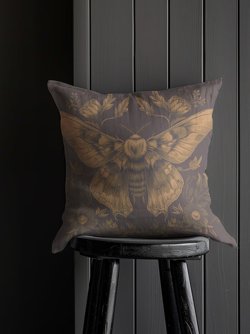 A decorative pillow cover featuring an intricately detailed Luna moth illustration in antique gold on a smoke gray background, surrounded by symmetrical botanical elements including flowers and delicate foliage.