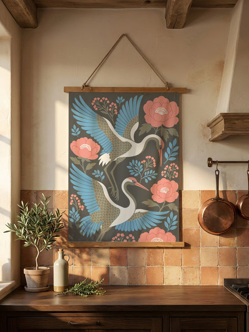 Vintage style Chinoiserie crane wall hanging by Grimoire and Goblet featuring two white cranes with light blue wings flying among coral pink peonies and sage green leaves against a dark charcoal grey background. The smooth polyester tapestry is suspended from artisanal wooden dowels with a natural twine hanger. A Grimoire and Goblet exclusive botanical design perfect for adding moody, Dark Academia ambiance to any apartment or sanctuary.