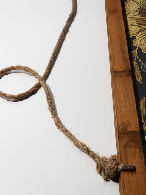 Botanical Hamsa wall tapestry featuring gold and teal design on black background, showing a protective hand symbol adorned with leaf motifs and floral elements, hanging from wooden dowels with natural twine.