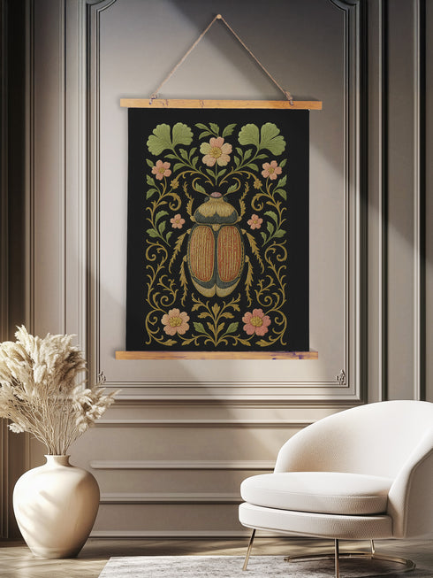 26x36 inch vertical wall tapestry printed on silky polyester fabric, featuring a detailed embroidered-style beetle surrounded by pink and green florals and curling botanical vines on a black background, with wooden hanger and twine at top and bottom. Art nouveau, vintage-inspired, cottagecore, gothic decor.