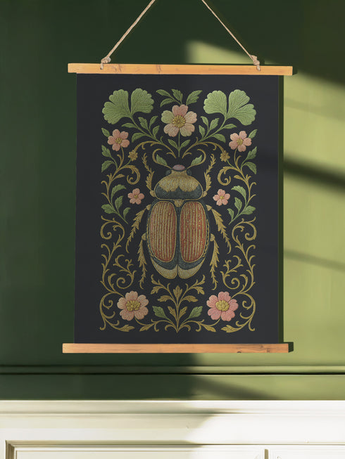 26x36 inch vertical wall tapestry printed on silky polyester fabric, featuring a detailed embroidered-style beetle surrounded by pink and green florals and curling botanical vines on a black background, with wooden hanger and twine at top and bottom. Art nouveau, vintage-inspired, cottagecore, gothic decor.