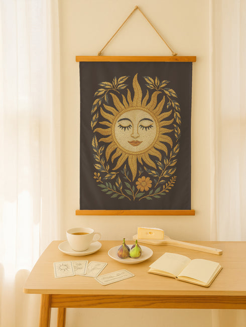 26x36 vertical tapestry featuring a feminine sun face surrounded by golden leaves and florals on a black background. Comes with stained wooden top and bottom dowels and natural twine for hanging. Made of silky polyester fabric with a smooth finish. Ideal for bohemian, celestial, or spiritual home decor themes.