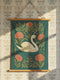 A 26x36 inch Art Nouveau wall scroll from Grimoire and Goblet. Crafted from silky premium polyester, it features a white swan with gold-accented feathers gliding through blue-green water, framed by vining olive foliage and salmon-pink chrysanthemums. A red-orange tulip blooms at the top. Suspended from stained wooden dowels with a natural twine rope, this tapestry evokes a mystical, gothic-botanical elegance.