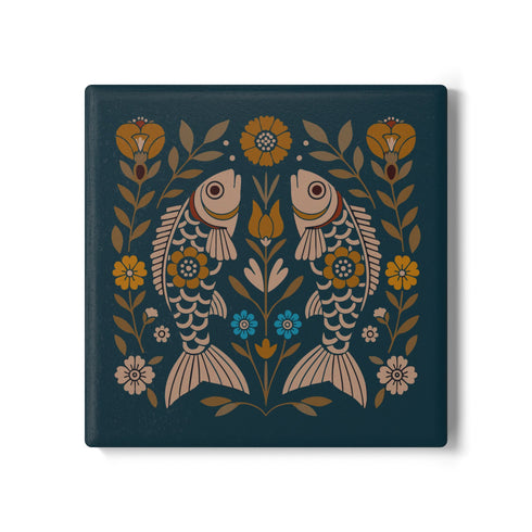 Square ceramic coaster, 4x4 inches, with cork backing. Teal tile features a folk-art twin fish motif framed by florals in mustard, cream, and soft blue. Smooth printed surface; crisp, flat color artwork. Witchy zodiac-inspired Pisces coaster for mystical home décor, coffee table protection, and gifting. Square ceramic drink coaster with cork base, teal fish design.