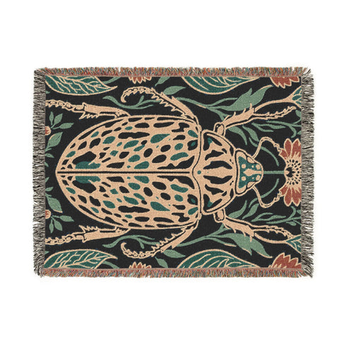 Jacquard woven 100% cotton blanket from Grimoire and Goblet featuring a detailed central beetle entomology motif and vintage botanical floral accents. The textile displays a rich woven texture with a fringe border in a dark academia palette of charcoal black, ochre, and rust. This heirloom-quality gothic tapestry functions as a decorative wall hanging or luxury throw for moody library and study interiors, showcasing high-fidelity thread-work and the brand's sorcerous aesthetic.