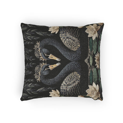 A double-sided woven jacquard throw pillow by Grimoire and Goblet measuring 17 by 18 inches. The tactile tapestry design features two black swans facing each other, their gracefully curved necks forming a subtle heart shape. Each swan wears a delicate floral crown in gold and cream tones. They float on a dark pond adorned with muted green lily pads and cream water lilies. The textured surface is woven from cotton and polyester threads.