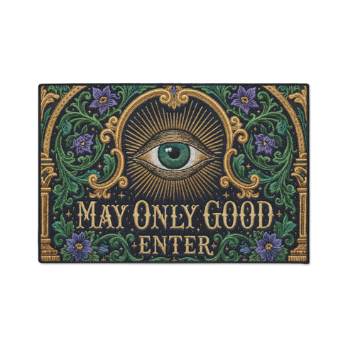 Rectangular doormat printed on a deep black ground with a faux embroidery effect that imitates antique crewelwork. A large green eye sits at the center within an antique gold radial sunburst, with ornate gold serif lettering below reading MAY ONLY GOOD ENTER. Green acanthus leaf scrollwork and antique gold architectural columns run along the borders, accented with small five petaled purple flowers. A sleek black trim frames all four edges of the flat printed surface.