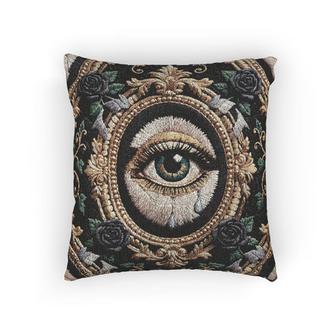 A square woven tapestry throw pillow by Grimoire and Goblet featuring a striking gothic design. The central motif is a large, detailed eye with a teal iris and light blue teardrops, set against pale skin. This eye is encased in an ornate, gold-toned baroque oval frame. The background is deep black, adorned with dark mauve roses and muted green foliage in the corners. The texture is a rich weave.