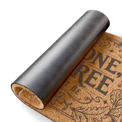A rectangular natural coir doormat featuring the Wiccan Rede "An' It Harm None, Do What Ye Will" in a gothic dark academia style. The central typography is surrounded by symmetrical botanical flourishes and mystical symbols printed in high-contrast black ink. The 2D flat print mimics the look of a vintage grimoire page on the coarse, tan coconut fiber surface. The mat has a durable black vinyl backing and is pictured at a front door as a protective threshold guardian.