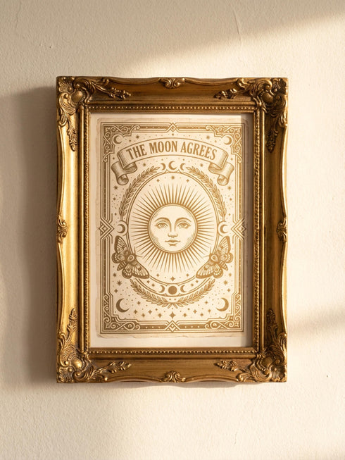 Grimoire and Goblet greeting card featuring a vintage woodcut style illustration of a radial sun with a serene human face. The sun is flanked by two Luna moths and sits above a Triple Moon symbol. A banner above reads THE MOON AGREES in gothic font. Printed in burnished gold tones on cream paper. Interior text reads Yours in this lifetime and the next. Dark Academia and Whimsigoth aesthetic stationery 5x7 card with matching envelope for gothic romance or altar decor.