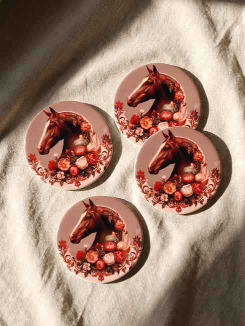 A round glazed ceramic coaster by Grimoire and Goblet featuring a vintage Victorian horse portrait design. The coaster has a high gloss porcelain-like finish and a natural cork bottom for furniture protection. The artwork depicts a dark bay horse head in profile surrounded by moody botanical flowers in shades of rust and deep red, evoking a dark academia and gothic cottagecore aesthetic. This 4x4 inch tile serves as a protective drink mat or decorative equine art accent.