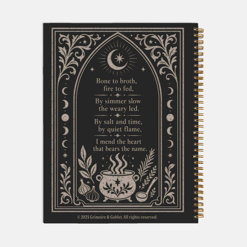 Spiral bound hardcover recipe journal lying flat. The matte black front cover is illustrated with light beige botanical vines, small crescent moons, a radial starburst, and a central cauldron releasing curls of steam, with classical lettering reading Spells of Bone and Broth. A black metal wire-o coil binds the left edge. The interior shows bright white pages printed with a structured recipe template, including labeled sections for ingredients and instructions, over a rigid chipboard backing.