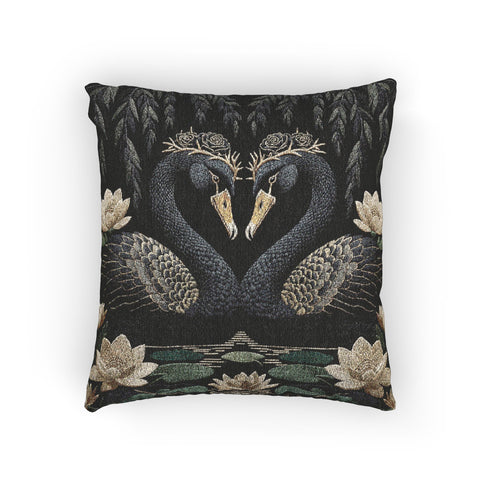 A double-sided woven jacquard throw pillow by Grimoire and Goblet measuring 17 by 18 inches. The tactile tapestry design features two black swans facing each other, their gracefully curved necks forming a subtle heart shape. Each swan wears a delicate floral crown in gold and cream tones. They float on a dark pond adorned with muted green lily pads and cream water lilies. The textured surface is woven from cotton and polyester threads.
