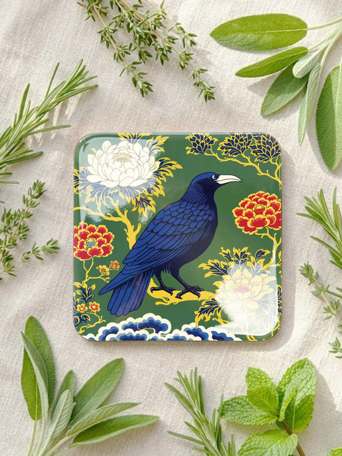 Grimoire and Goblet set of 4 glossy square coasters featuring Chinoiserie style raven illustrations. 1: Navy blue with blue floral pattern and raven. 2: Navy background with black raven, white full moon, and red berries. 3: Moss green background with blue bird and yellow chrysanthemums. 4: Black background with teal-winged raven and red peonies. MDF hardboard with cork backing. Flat vector botanical art style.
