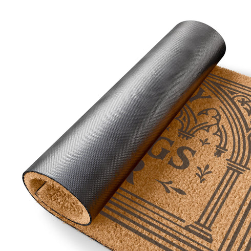 A rectangular natural brown coir doormat with a rugged texture and a durable black vinyl backing. The doormat features an intricate black design framed by a gothic arch with stylized quatrefoil details in the corners. Inside the arch, the words "MAY ONLY BLESSINGS ENTER" are printed in an elegant, bold serif font. A central sunburst medallion with radiating lines sits above the text, reinforcing the spiritual and protective theme of this gothic entryway welcome mat.