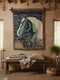 a large tapestry hanging on a wall, depicting a horse with a blue background and green accents. Below the tapestry, there is a wooden bench with a blanket and a basket of yarn. The room also has a window, a potted plant, and some dried flowers hanging from the ceiling.