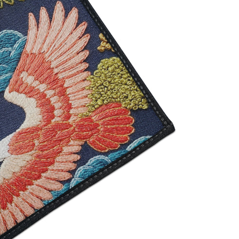 Grimoire and Goblet chinoiserie flying crane faux embroidery doormat featuring three cranes in coral blush and jade green soaring across deep navy background with teal scalloped clouds golden bonsai branches and olive foliage. Printed polyester entryway mat with non-slip rubber backing and black trim. Available 24x18 and 36x24 inches. Asian inspired Japanese crane design housewarming gift home decor