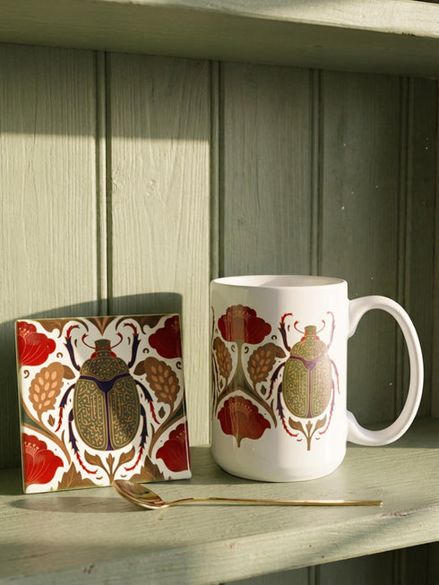 A luxury gift set featuring a matching ceramic mug and square coaster with a vintage entomology design. The artwork depicts a vibrant green Scarab beetle with iridescent wings, surrounded by dark moody floral botanicals in rust and ochre, set against a creamy background in a Victorian naturalist style. The mug is 15oz with a large handle and full wrap design. The coaster is glazed ceramic tile with a cork backing. Perfect for Dark Academia and Grimoire and Goblet gothic home decor.