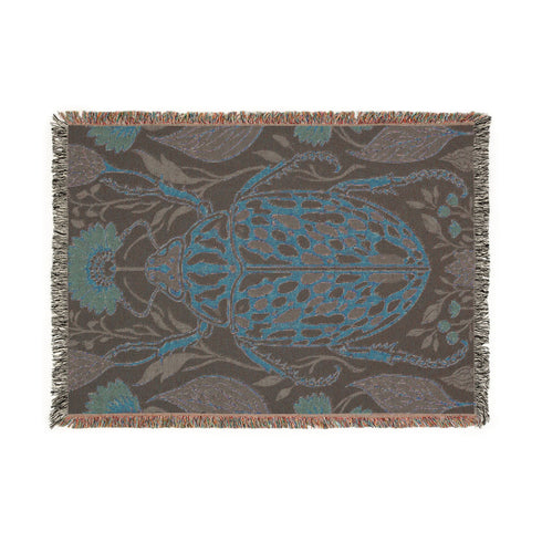 Jacquard woven 100% cotton blanket from Grimoire and Goblet featuring a detailed central beetle entomology motif and vintage botanical floral accents. The textile displays a rich woven texture with a fringe border in a dark academia palette of charcoal black, ochre, and rust. This heirloom-quality gothic tapestry functions as a decorative wall hanging or luxury throw for moody library and study interiors, showcasing high-fidelity thread-work and the brand's sorcerous aesthetic.