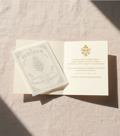 a luxury Grimoire and Goblet ritual card set. A 5x7 cream-colored folded card features an intricate, art-nouveau-style gold foil illustration of a Juniper plant, with the words "Juniper: Cleansing & Fortune." The card is presented with a translucent vellum envelope, which has a gold floral border and a white adhesive wax seal. Inside, the card reveals a vellum-wrapped keepsake, which unfurls to a 4x6 ritual card printed on thick, 160 GSM handmade cotton paper with a rough, deckled edge.