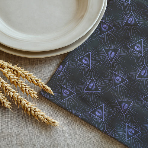 Set of four charcoal-colored cloth napkins with a repeating pattern of triangular all-seeing eyes in purple, surrounded by radiating lines and small star-like accents.