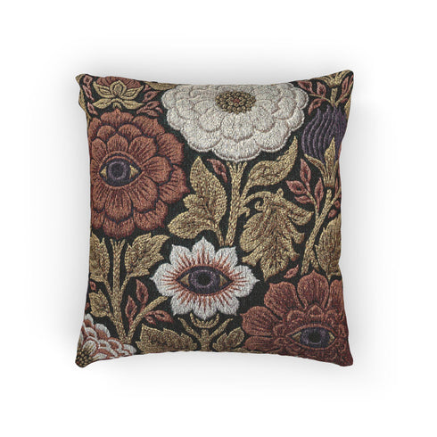 A square woven throw pillow featuring a surreal botanical design on a solid black background. The tapestry-style fabric showcases large, detailed flowers in shades of rust red, cream, and olive green. Nestled within the center of each prominent blossom is a detailed, human-like eye with a dark plum iris, creating a striking evil eye motif. The interwoven threads give the pillow a rich, textured appearance. The pillow is fully stuffed and sewn closed, presenting a smooth, seamless edge.