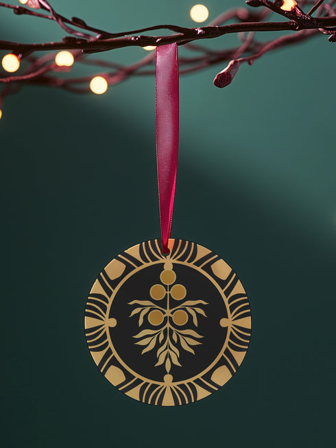 Round metal ornament featuring golden juniper berry branch design with Art Deco-inspired geometric border on black background. 3.5-inch diameter piece with botanical motif and crimson ribbon. Double-sided detailed artwork.