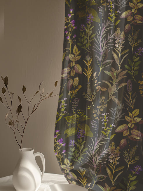 Sheer curtain panel featuring an intricate vertical pattern of wild botanicals including purple flowers, golden leaves, and silvery fronds against a dark charcoal background. The design shows detailed herbarium-style illustrations.