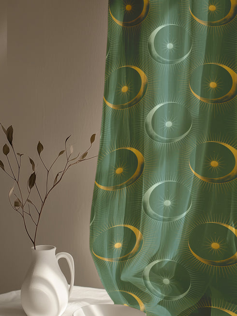 Sheer forest green curtain panel featuring repeating pattern of golden suns and silver moons with radiating lines, creating an elegant celestial motif against translucent fabric.
