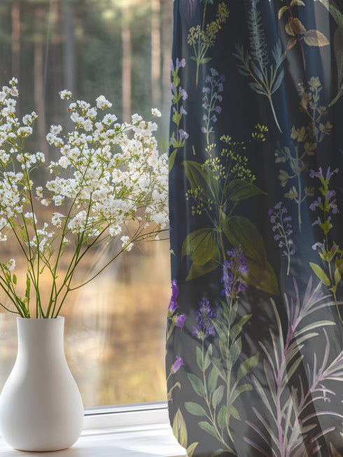 Sheer curtain panel featuring an intricate vertical pattern of wild botanicals including purple flowers, golden leaves, and silvery fronds against a dark charcoal background. The design shows detailed herbarium-style illustrations.