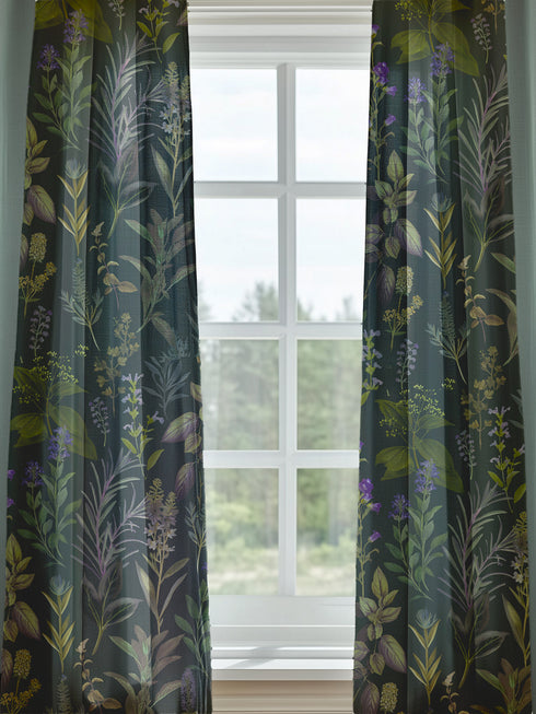 Sheer curtain panel featuring an intricate vertical pattern of wild botanicals including purple flowers, golden leaves, and silvery fronds against a dark charcoal background. The design shows detailed herbarium-style illustrations.