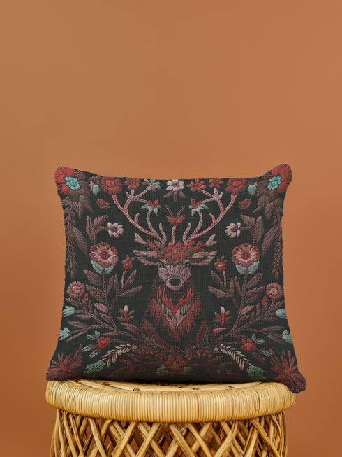 Woven throw pillow featuring an embroidered stag with antlers entwined in red and teal florals, set against a black background.