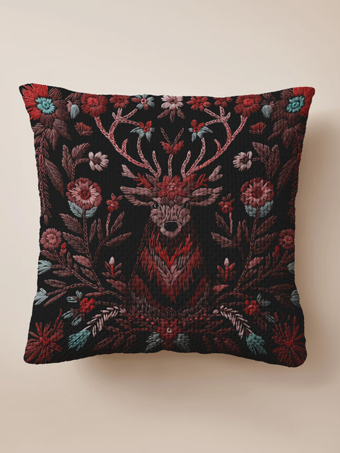 Woven throw pillow featuring an embroidered stag with antlers entwined in red and teal florals, set against a black background.