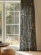 Sheer curtain panel featuring an intricate vertical pattern of wild botanicals including purple flowers, golden leaves, and silvery fronds against a dark charcoal background. The design shows detailed herbarium-style illustrations.
