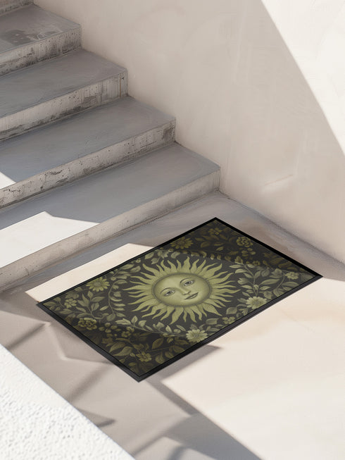 Witchy home décor doormat with an enchanting olive green sun face surrounded by flowing botanicals and foliage on a rich black background, ideal for adding earth-centered mysticism to any entrance.