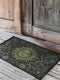 Witchy home décor doormat with an enchanting olive green sun face surrounded by flowing botanicals and foliage on a rich black background, ideal for adding earth-centered mysticism to any entrance.