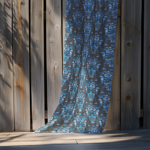 A sheer curtain panel featuring a repeating pattern of stylized owls in luminous blue tones, surrounded by delicate botanical flowers and flourishes on a dark background.